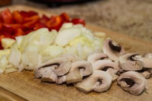 Self Catering geschnittenen Pilze, Zwiebeln und Paprika auf einem Holzbrett